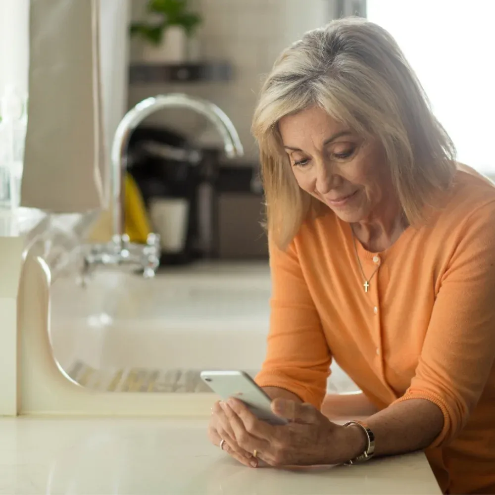A senior woman checking her glucose readings on her phone at home